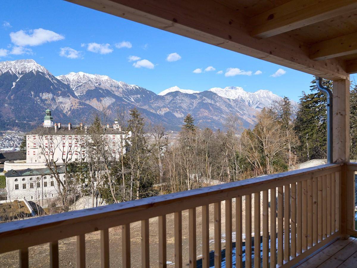Holzbalkon mit weitem Blick auf die Stadt und die majestätischen Alpen.