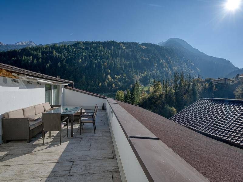 Weitläufige Dachterrasse mit bequemen Loungemöbeln und Panoramablick auf die Alpenlandschaft.
