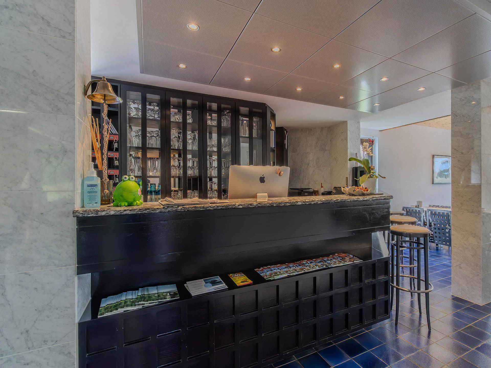 Empfangsbereich mit Bar, dunkler Theke und blauen Fliesenboden.