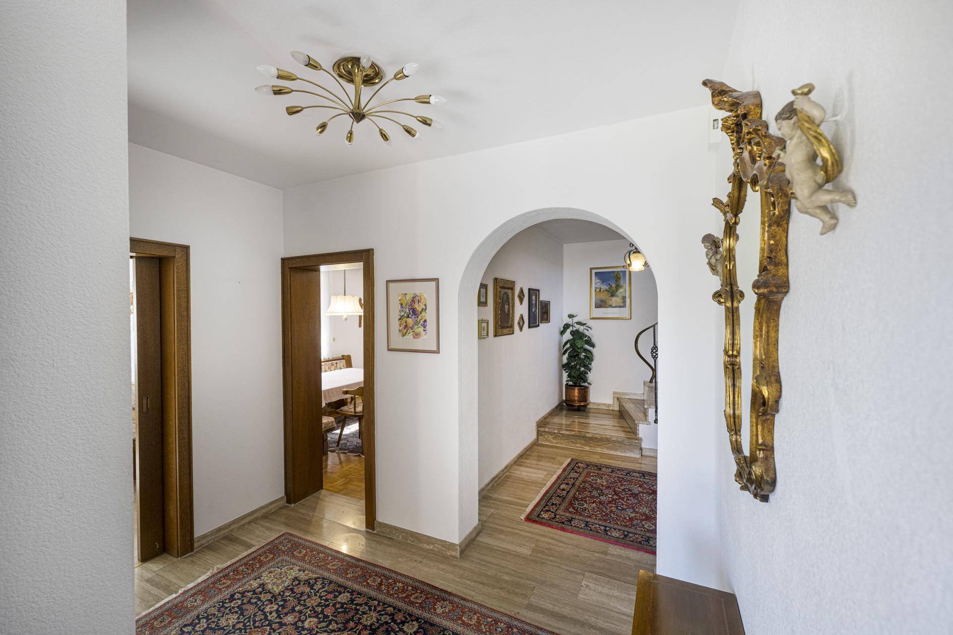 Heller Flur mit elegantem Bogen, Treppenaufgang und traditioneller Wanddekoration.