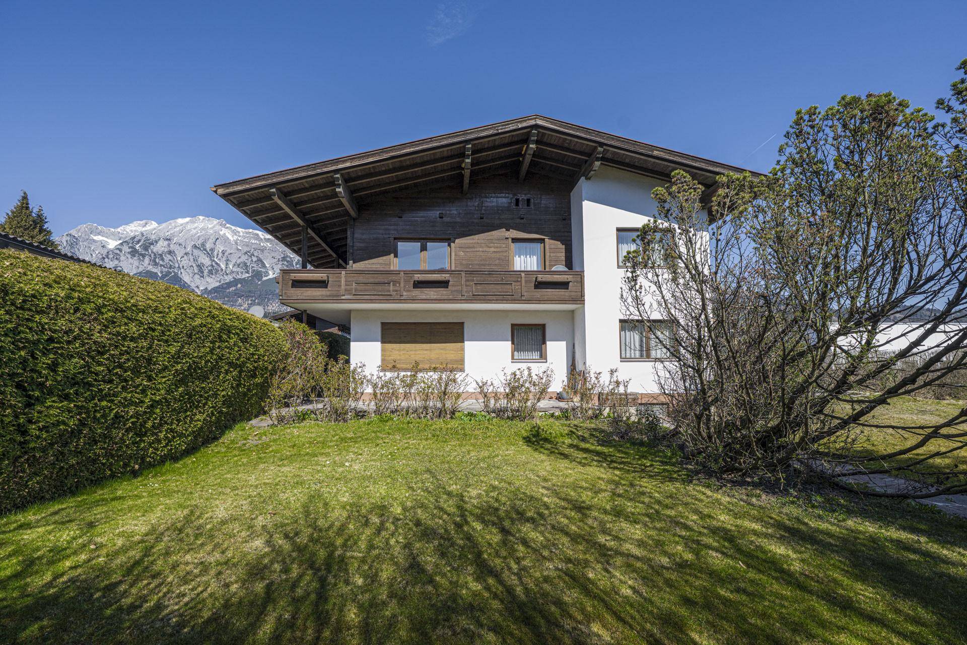Traditionelles Haus mit Holzbalkonen, gepflegtem Garten und majestätischem Bergblick.