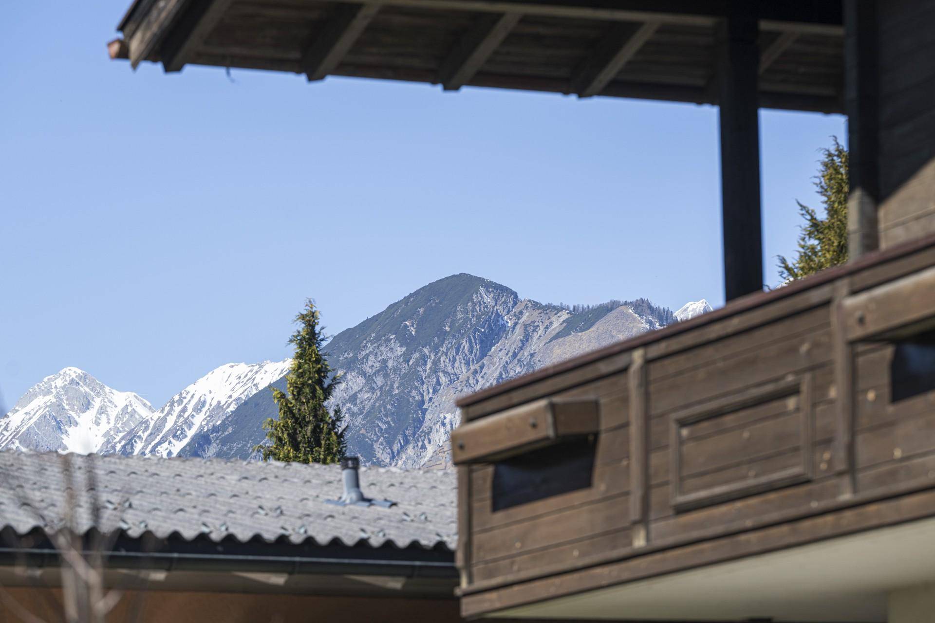 Holzbalkon mit Blick auf die majestätischen schneebedeckten Berge unter klarem Himmel.