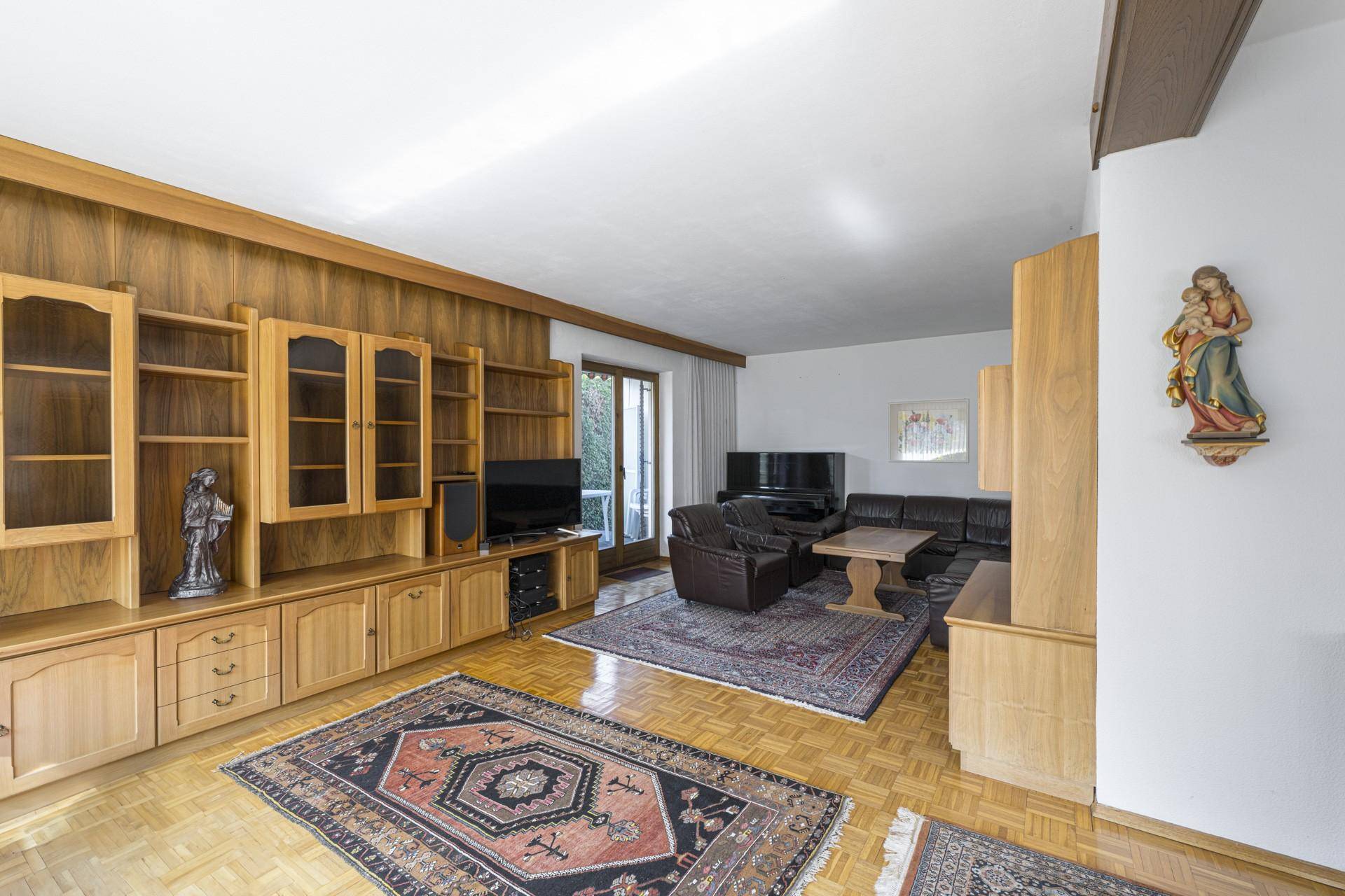 Geräumiges Wohnzimmer mit Holzvertäfelung, bequemer Ledercouch und Zugang zum Außenbereich.