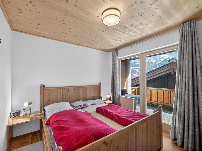 Schlafzimmer mit Holzbett, Holzdecke und direktem Zugang zu einem Balkon mit Bergblick.