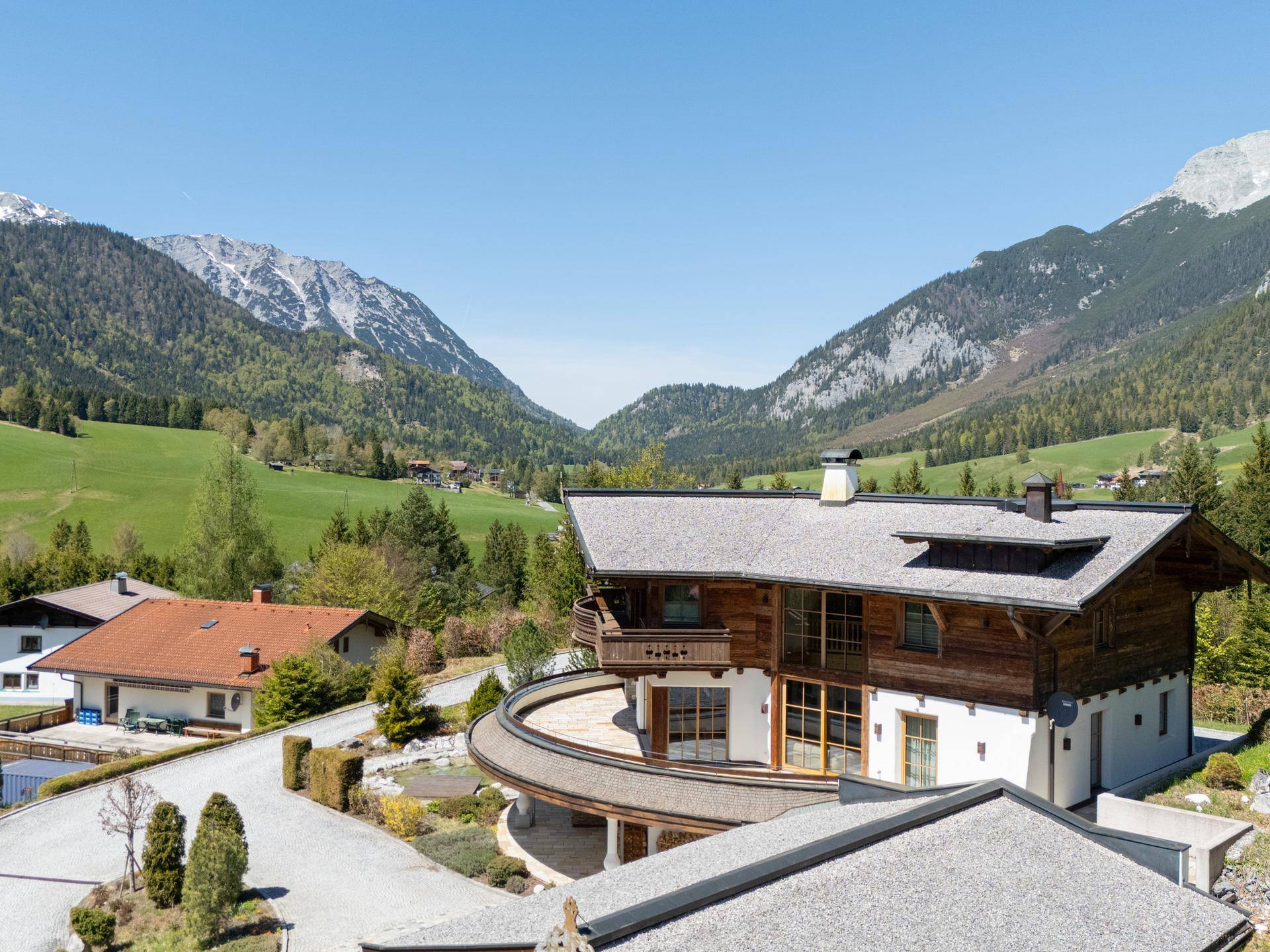 Alpenländisches Chalet mit weitem Blick auf die umliegende Berglandschaft und grüne Täler.