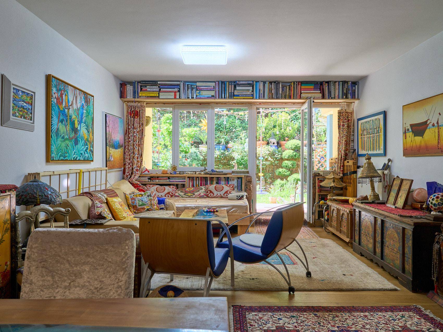 Geräumiges Wohnzimmer mit bequemen Möbeln, Kunstwerken und Blick auf den üppigen Garten.