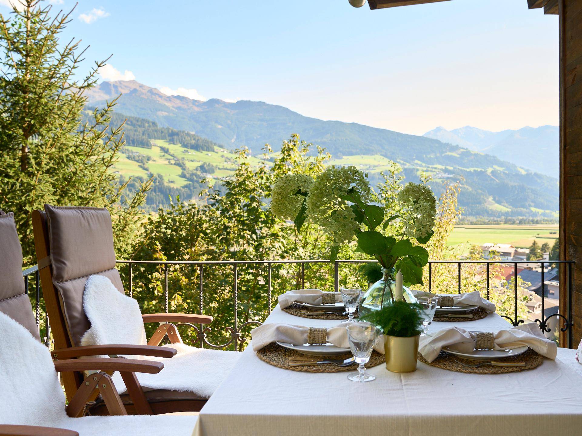 Einladende Terrasse mit gedecktem Tisch und atemberaubendem Bergblick an einem sonnigen Tag.