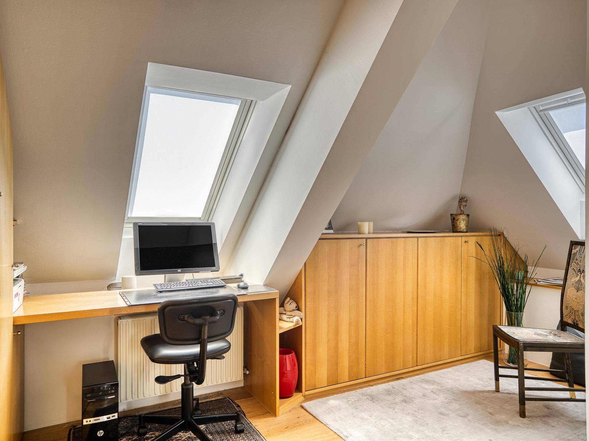 Funktionales Home-Office im Dachgeschoss mit Schreibtisch, integrierten Schränken und Dachfenster.
