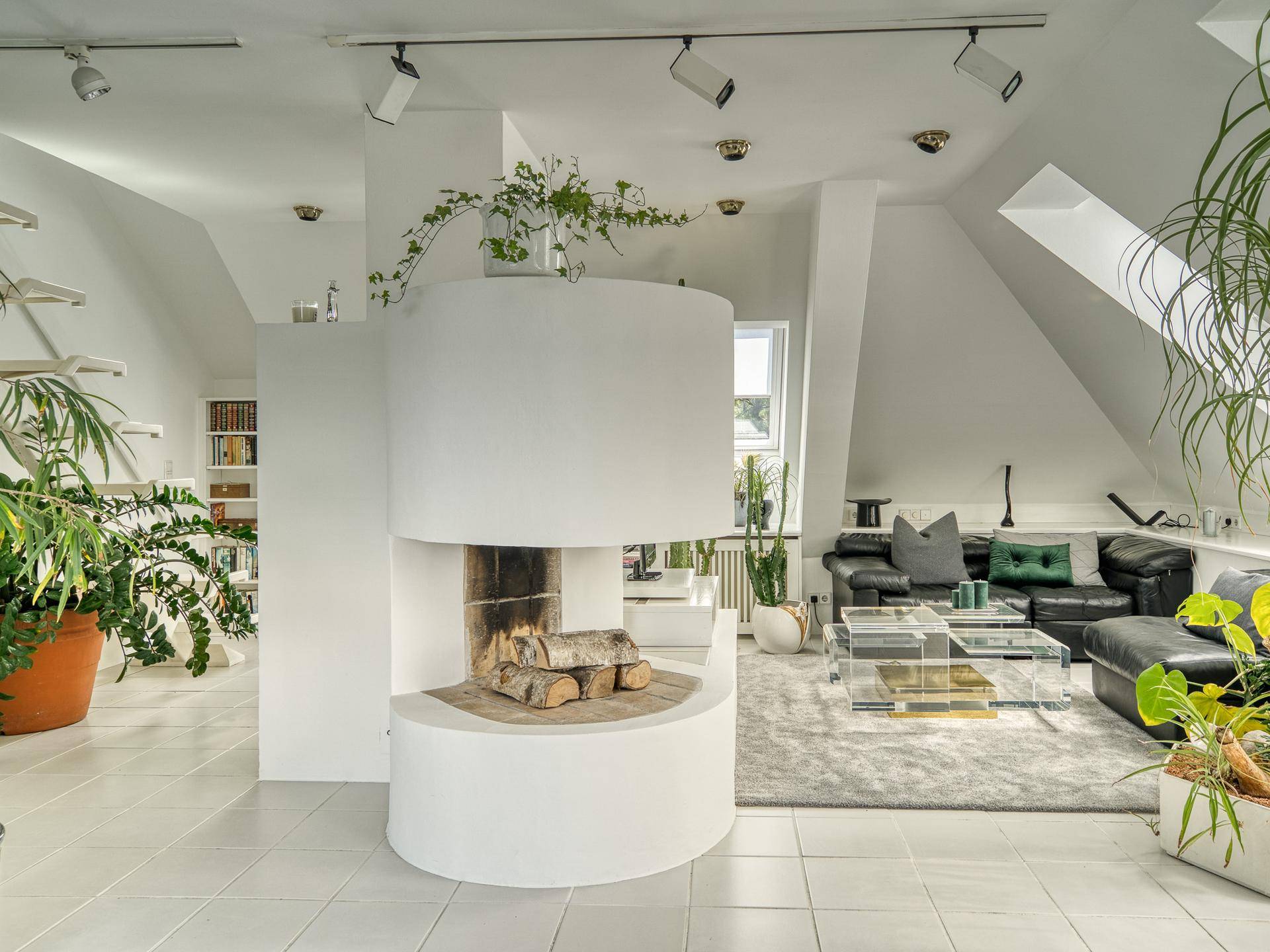 Lichtdurchflutetes Wohnzimmer mit elegantem Kamin, Ledersofa und stilvoller Einrichtung im Dachgeschoss.