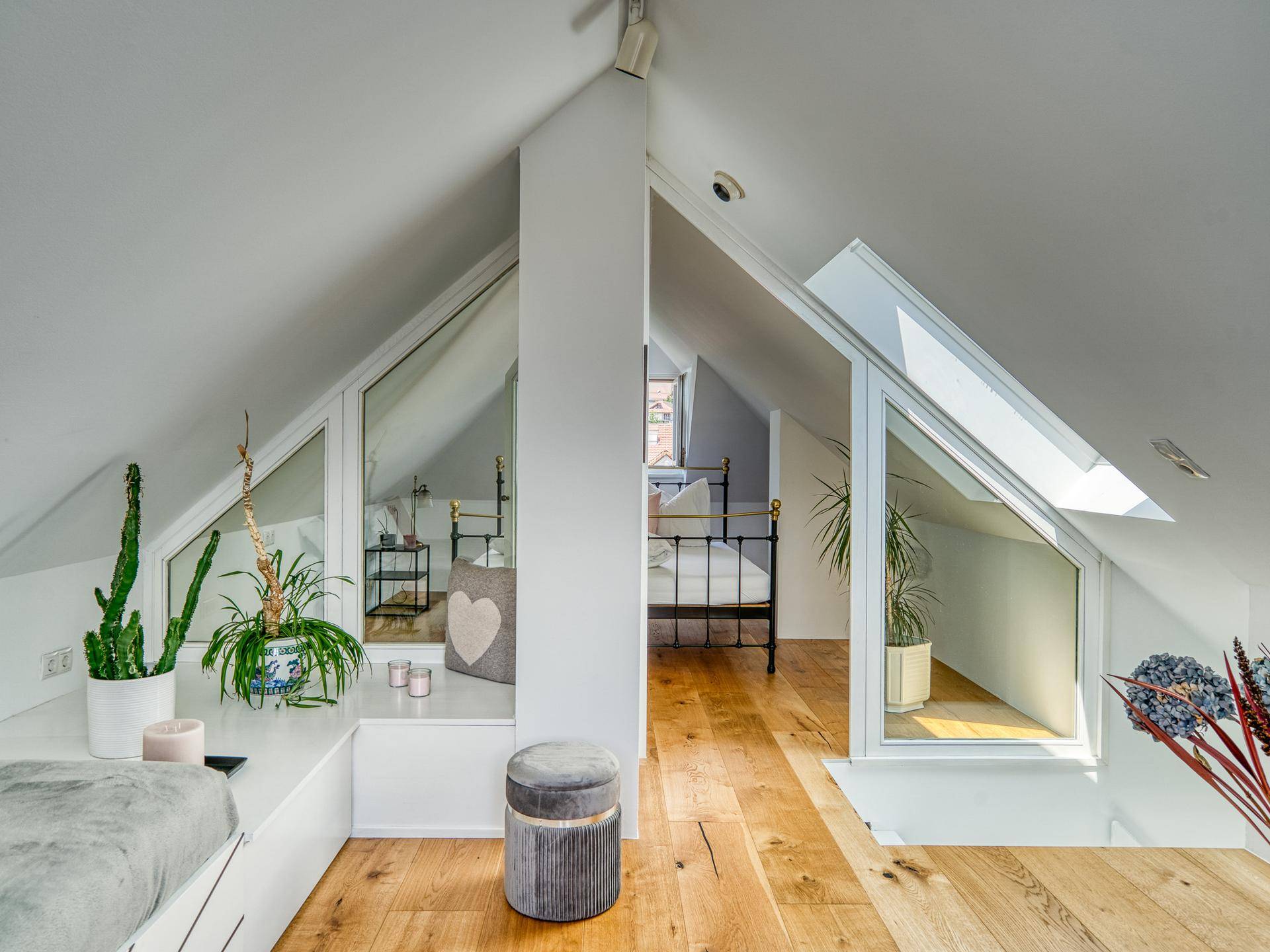 Helles Dachgeschoss-Schlafzimmer mit Holzboden, schrägen Wänden und integrierten Dachfenstern für viel Licht.