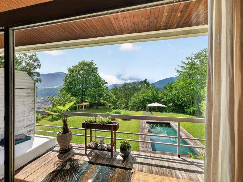 Blick vom Balkon auf den Garten mit Pool, die Stadt und die umliegende Berglandschaft.