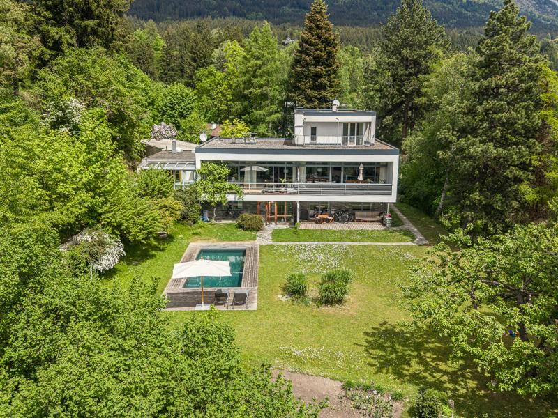 Großzügiger Gartenbereich mit Swimmingpool und Liegewiese, umgeben von üppigem Grün und dem modernen Haus.