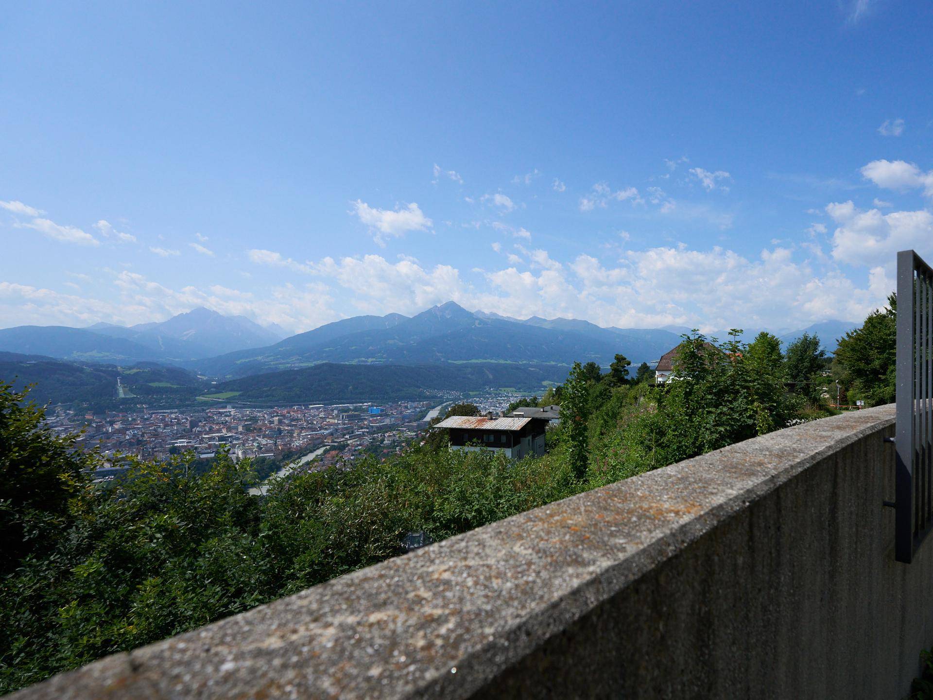 Panoramablick über die Stadt und die umliegende Berglandschaft an einem sonnigen Tag.