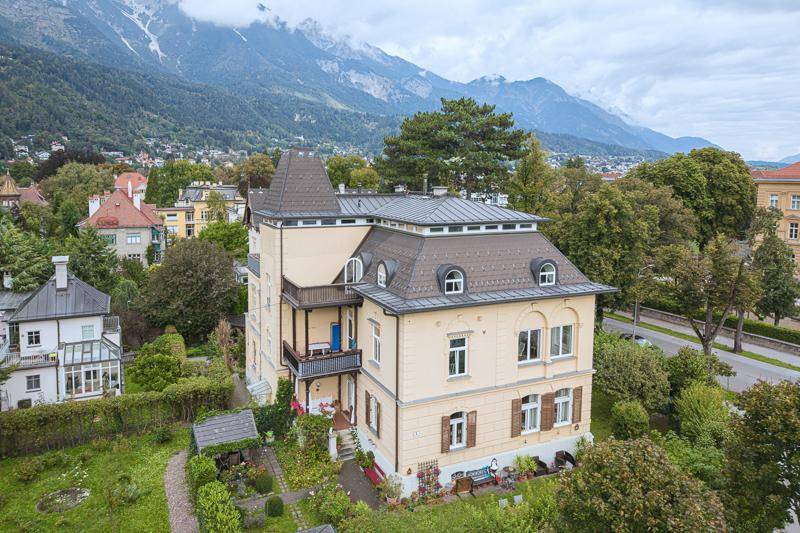 Historische Villa mit markanter Architektur, umgeben von viel Grün und beeindruckendem Bergblick.