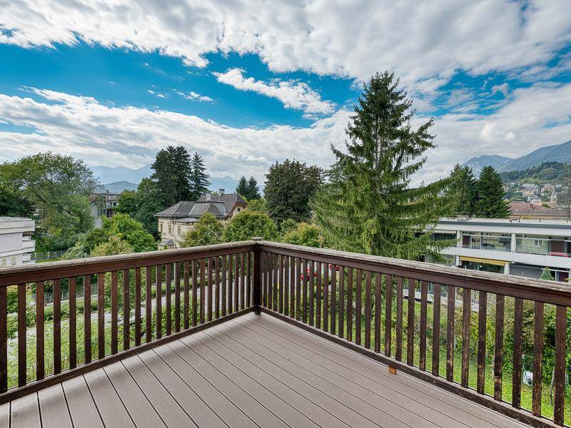Geräumiger Holzbalkon mit weitem Blick über die Baumwipfel und die umliegende Landschaft.