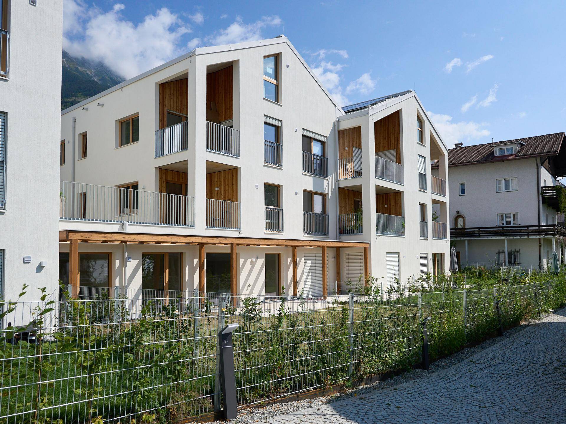 Neubau-Wohngebäude mit moderner Architektur, Holzelementen und Balkonen in einer grünen Umgebung.