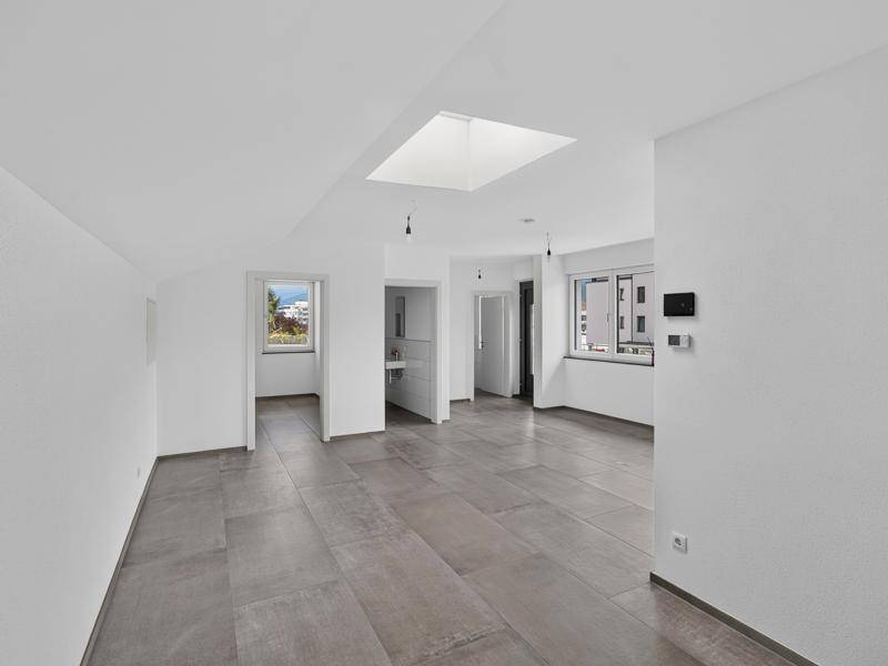 Großer, heller Raum mit Oberlicht, Fliesenboden und mehreren Türöffnungen, bereit zum Ausbau.