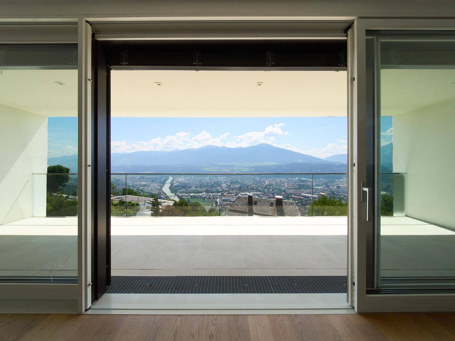 Heller Innenraum mit Zugang zum Balkon und weitem Blick über die Stadt und die Berge.