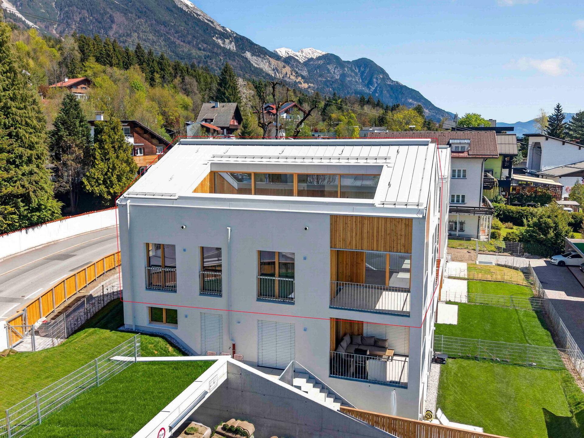 Moderne Architektur eines Mehrfamilienhauses mit Balkonen und Blick auf die umliegende Berglandschaft.