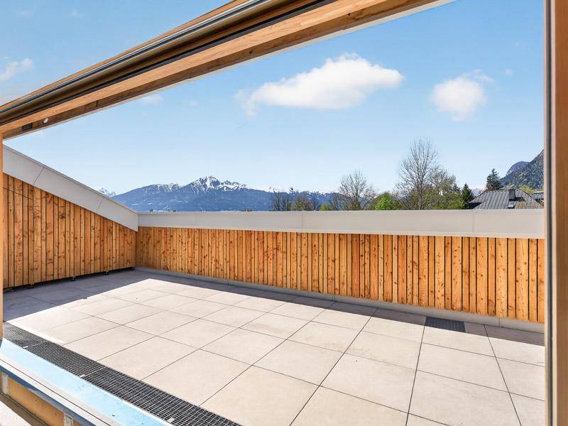 Geräumige, leere Terrasse mit Fliesenboden und weitem Blick auf die schneebedeckten Berge.