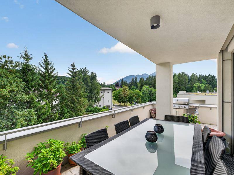 Geräumige Terrasse mit Esstisch, Grillbereich und Panoramablick auf die Berge.