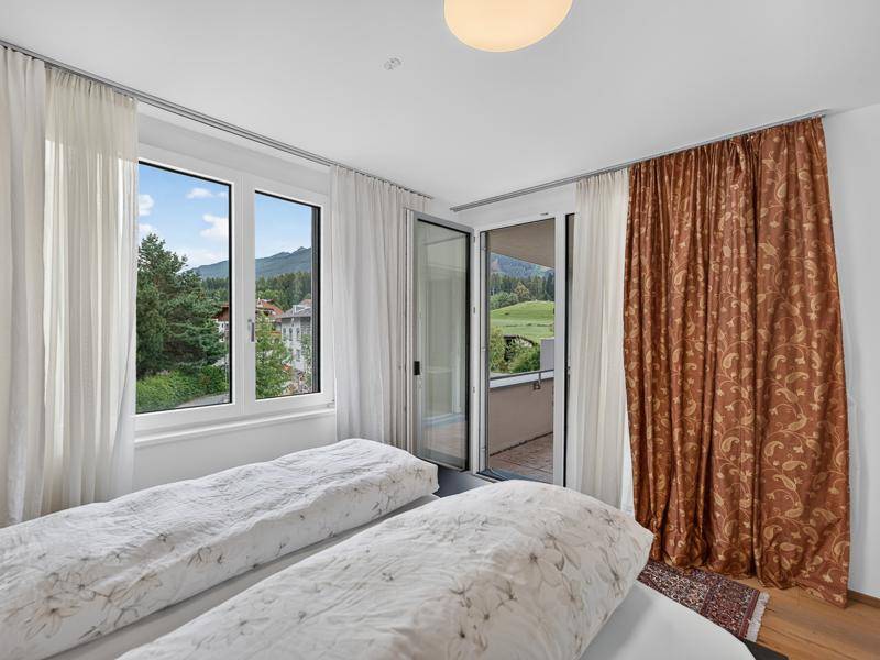 Helles Schlafzimmer mit großem Fenster, Balkonzugang und Blick auf die umliegende Natur.