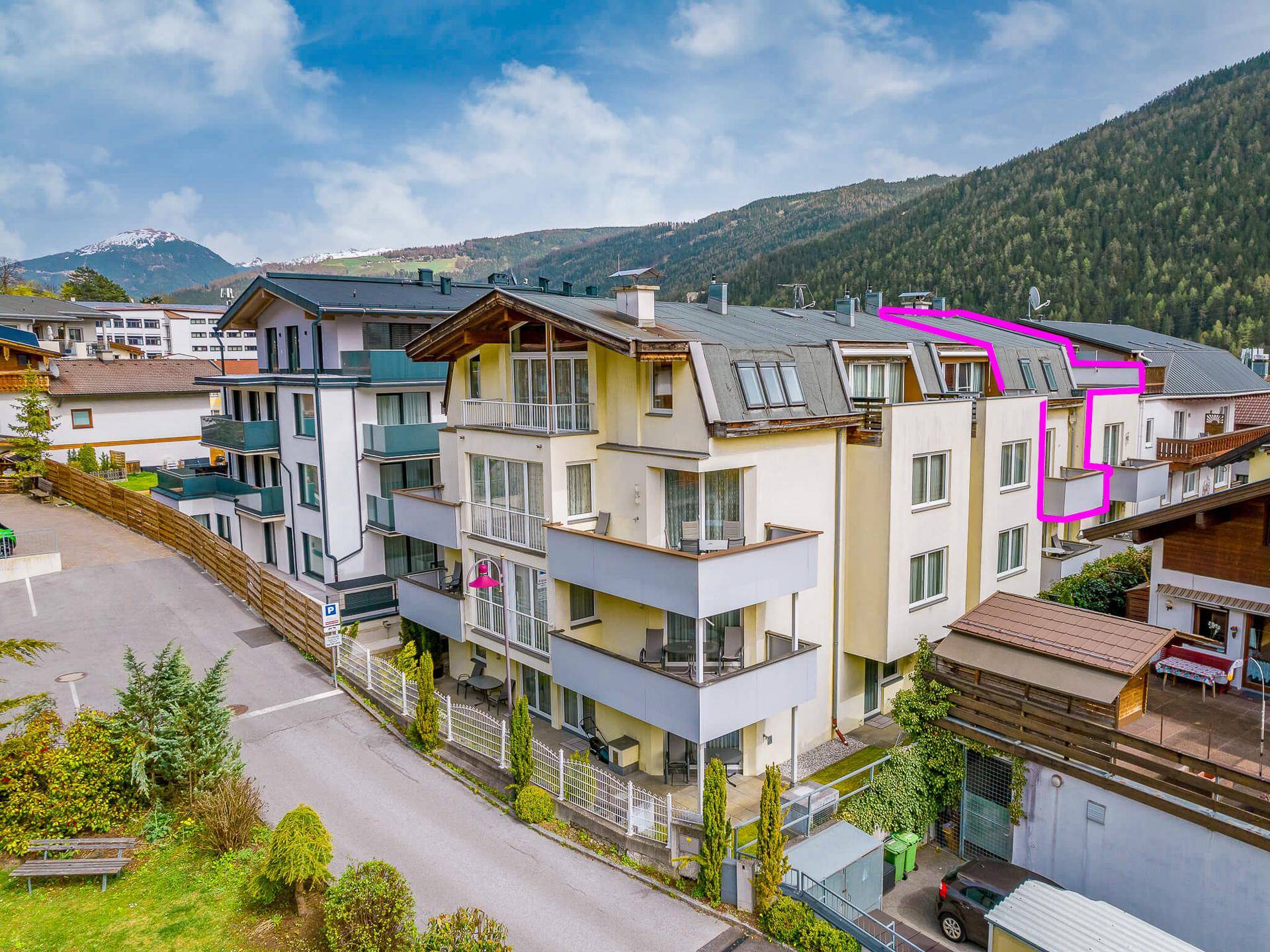 Mehrfamilienhaus in alpiner Umgebung mit Balkonen und Bergblick.
