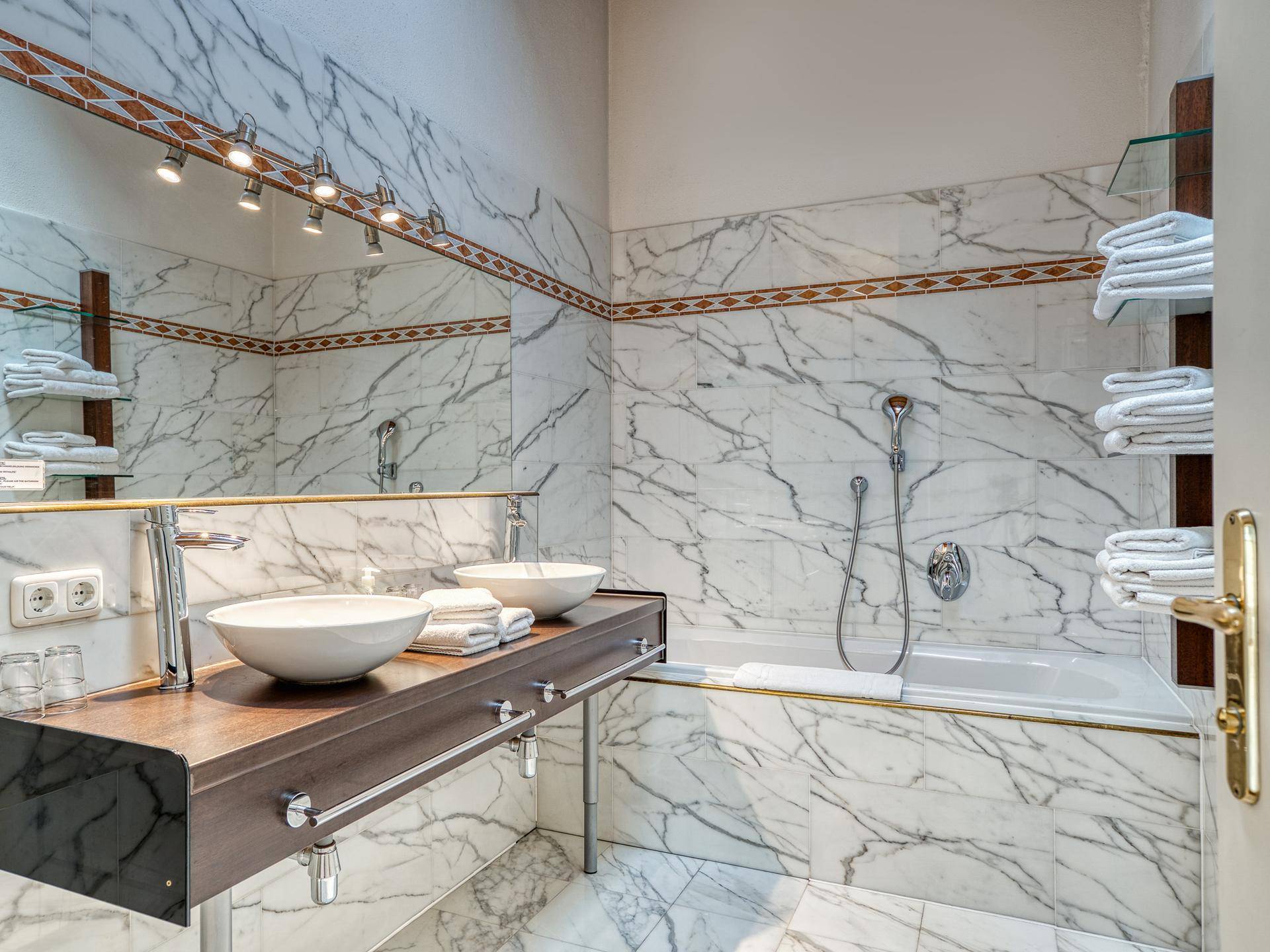 Elegantes Badezimmer mit Marmorfliesen, Doppelwaschbecken und Badewanne.
