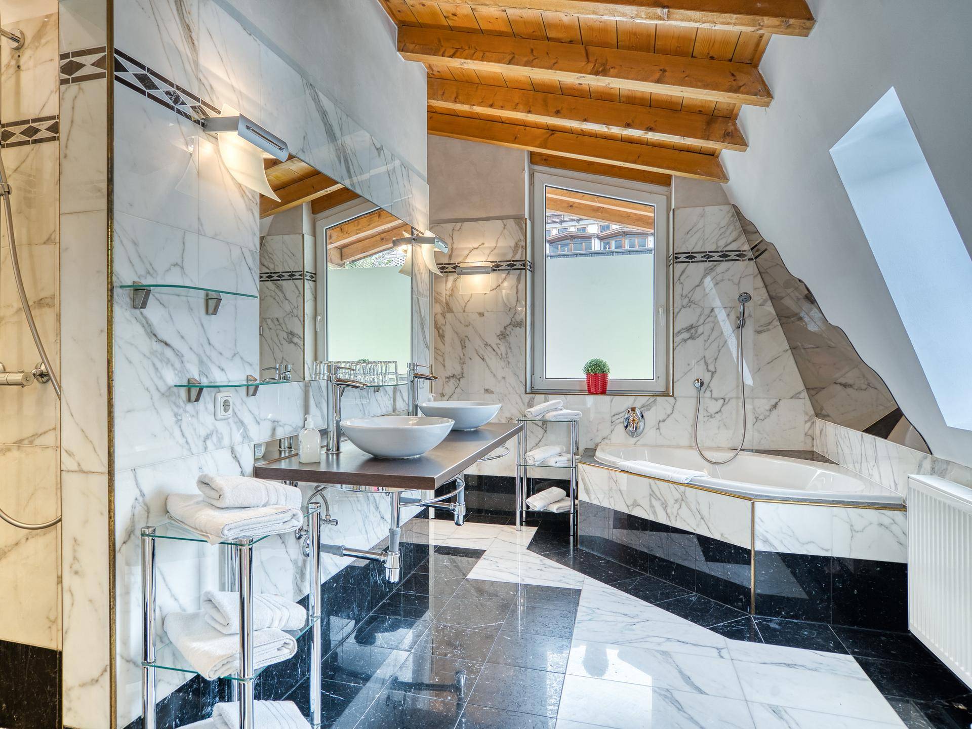 Luxuriöses Badezimmer mit Marmorfliesen, Doppelwaschbecken, Eckbadewanne und Holzbalkendecke.