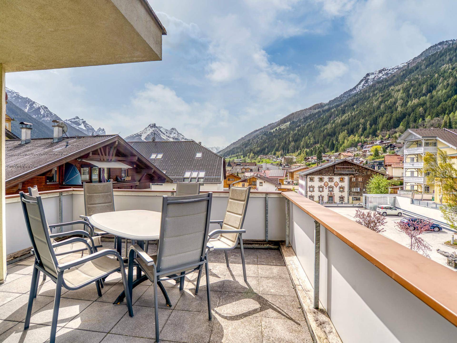 Sonniger Balkon mit Sitzgelegenheiten und atemberaubendem Blick auf die umliegende Berglandschaft.
