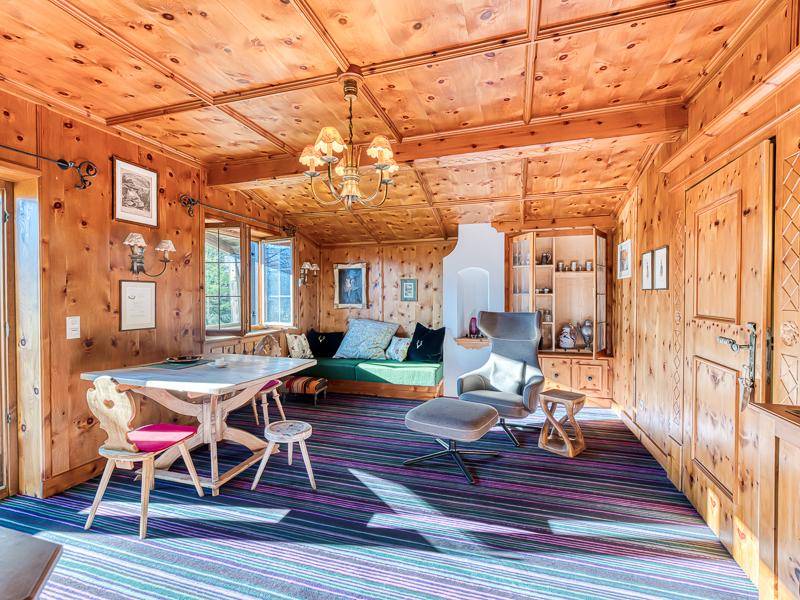Gemütliches Wohnzimmer im alpinen Stil mit Holztäfelung, bunten Teppichen und traditionellen Möbeln.