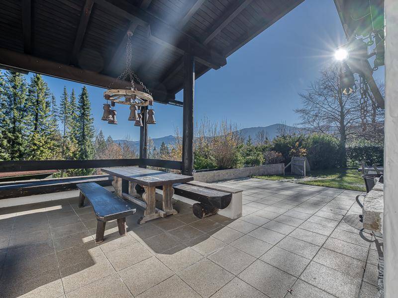 Sonnige Terrasse mit Holztisch, Bänken und weitem Blick auf die umliegende Berglandschaft.