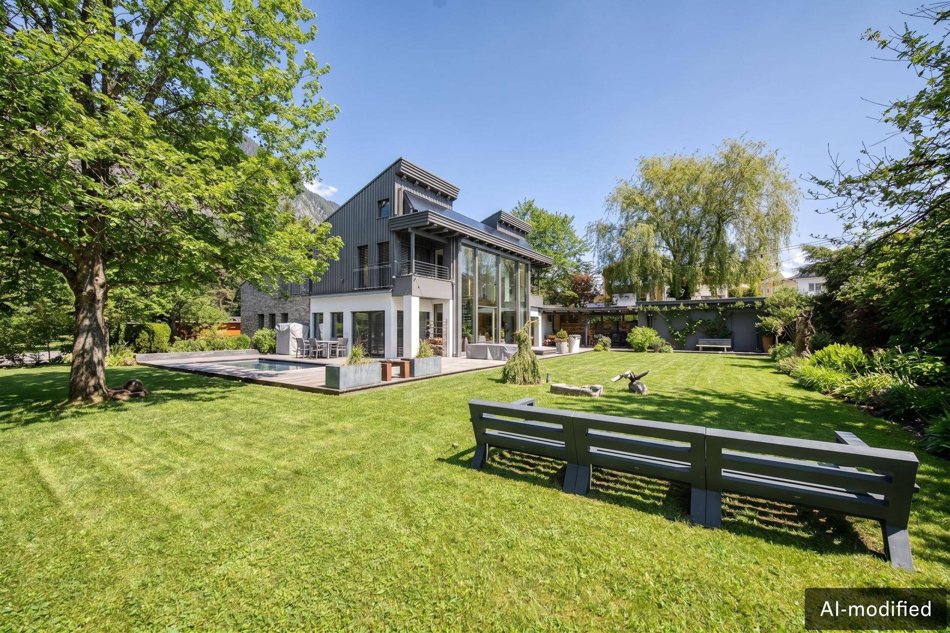 Elegante moderne Villa mit weitläufigem Garten, Pool und beeindruckender Bergkulisse.