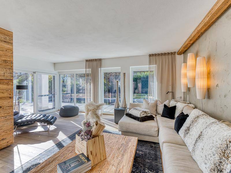 Helles Wohnzimmer mit großen Glasfronten, Holzakzenten und einem gemütlichen Ecksofa.