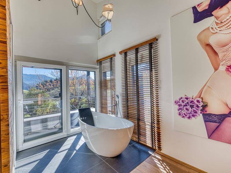 Modernes Badezimmer mit freistehender Badewanne und großen Fenstern, die einen weiten Blick bieten.
