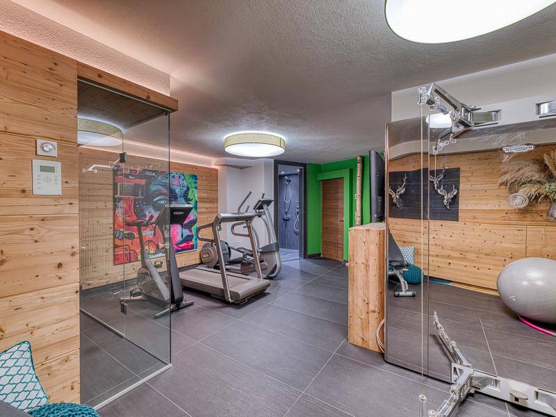 Gut ausgestatteter Fitnessraum mit Holzverkleidung, Laufband und Spiegelwand für das tägliche Training.