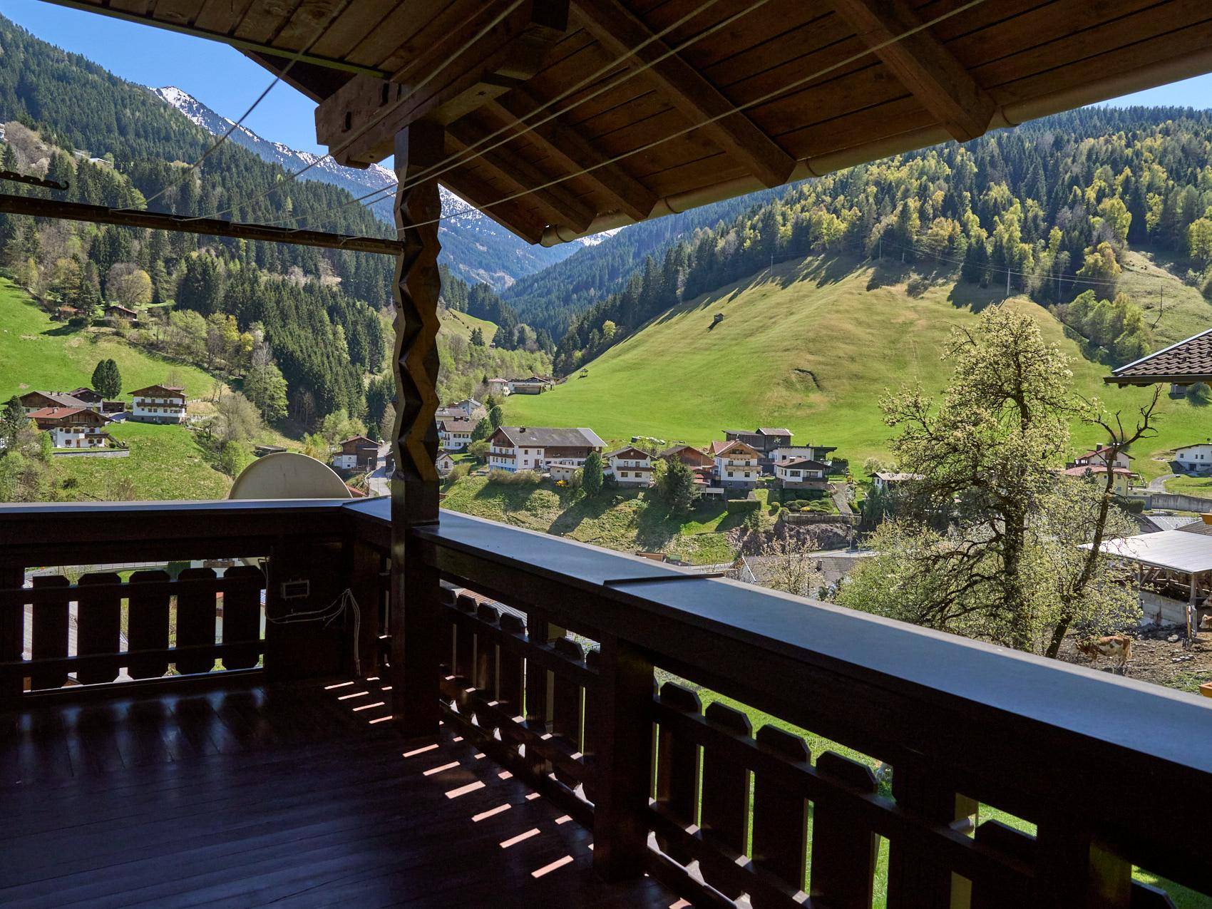 Überdachter Holzbalkon mit atemberaubendem Blick auf die grünen Berge und das Tal.
