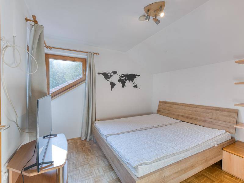 Gemütliches Schlafzimmer im Dachgeschoss mit Holzbett, Dachschräge und Parkettboden.