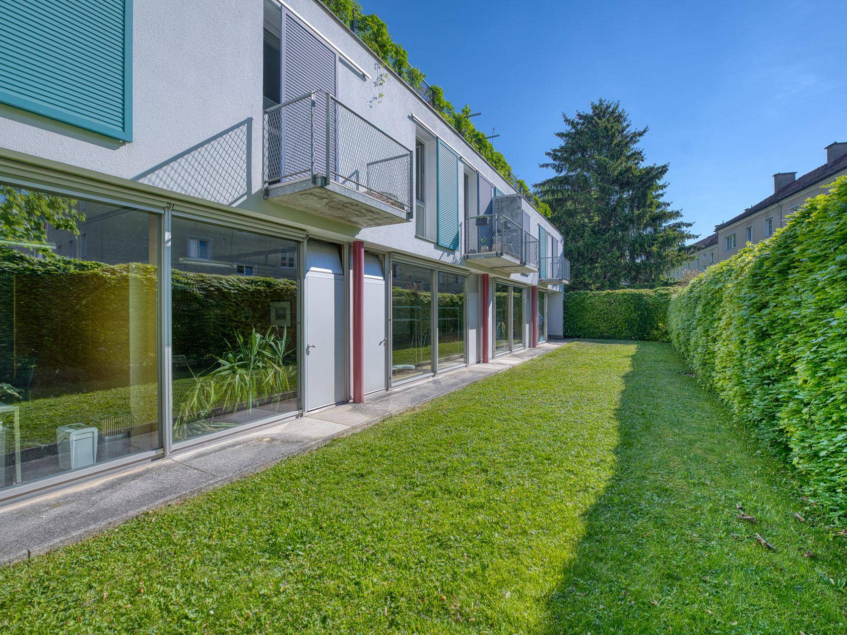 Moderne Gebäudefassade mit großen Fensterfronten und gepflegtem Rasenbereich.