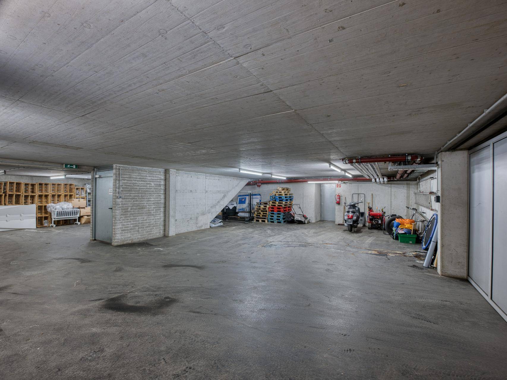 Geräumiger Kellerraum mit Betonboden, Lagerflächen und sichtbaren Installationen.