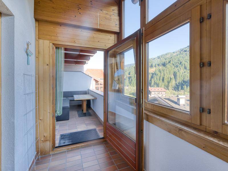 Überdachte Loggia mit Holzelementen, Sitzgelegenheit und Blick auf die umliegende Bergwelt.
