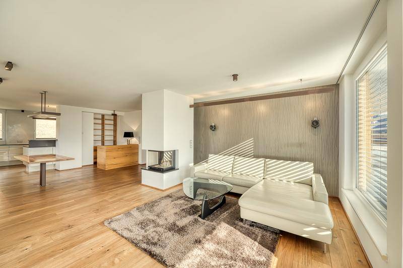Heller Wohnbereich mit bequemer Couch, modernem Kamin und Holzboden in einem offenen Grundriss.