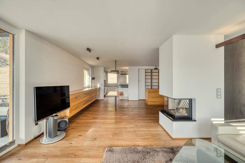Geräumiger offener Wohnbereich mit Holzboden, Kamin und Blick auf den Ess- und Küchenbereich.