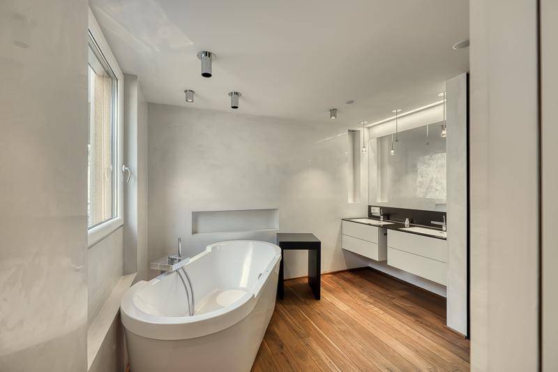 Modernes Badezimmer mit freistehender Badewanne, Doppelwaschbecken und Fenster für Tageslicht.