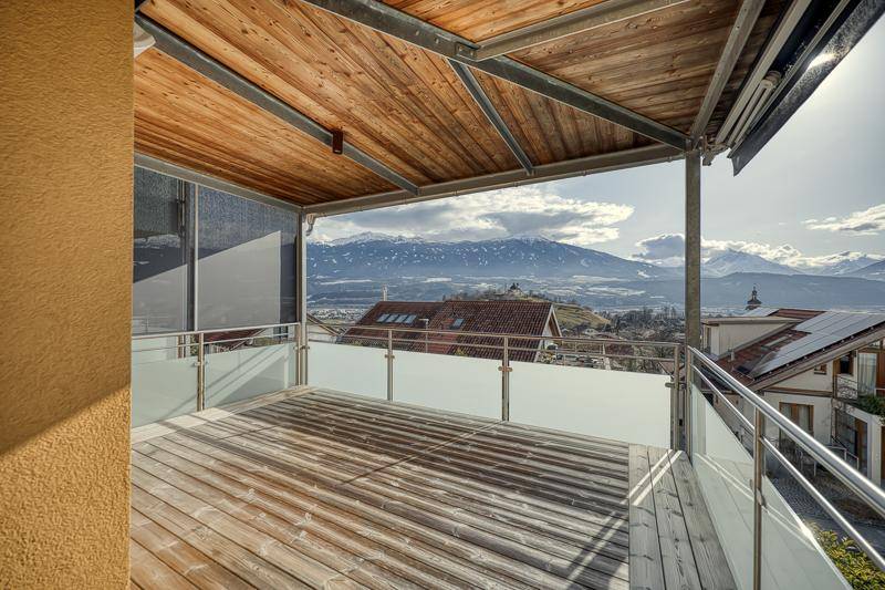 Großer überdachter Balkon mit Holzboden und spektakulärem Panoramablick auf die umliegenden Berge.