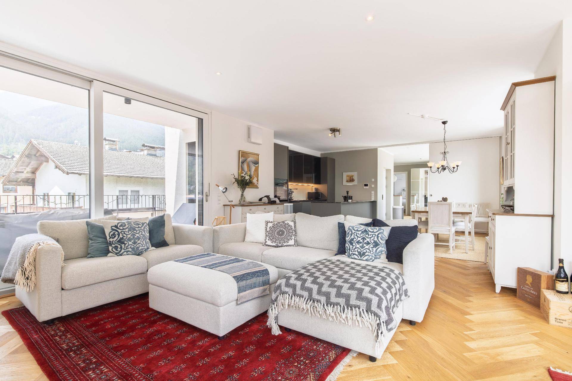 Gemütliches Wohnzimmer mit großem Sofa, Zugang zum Balkon und Blick auf die Berge.