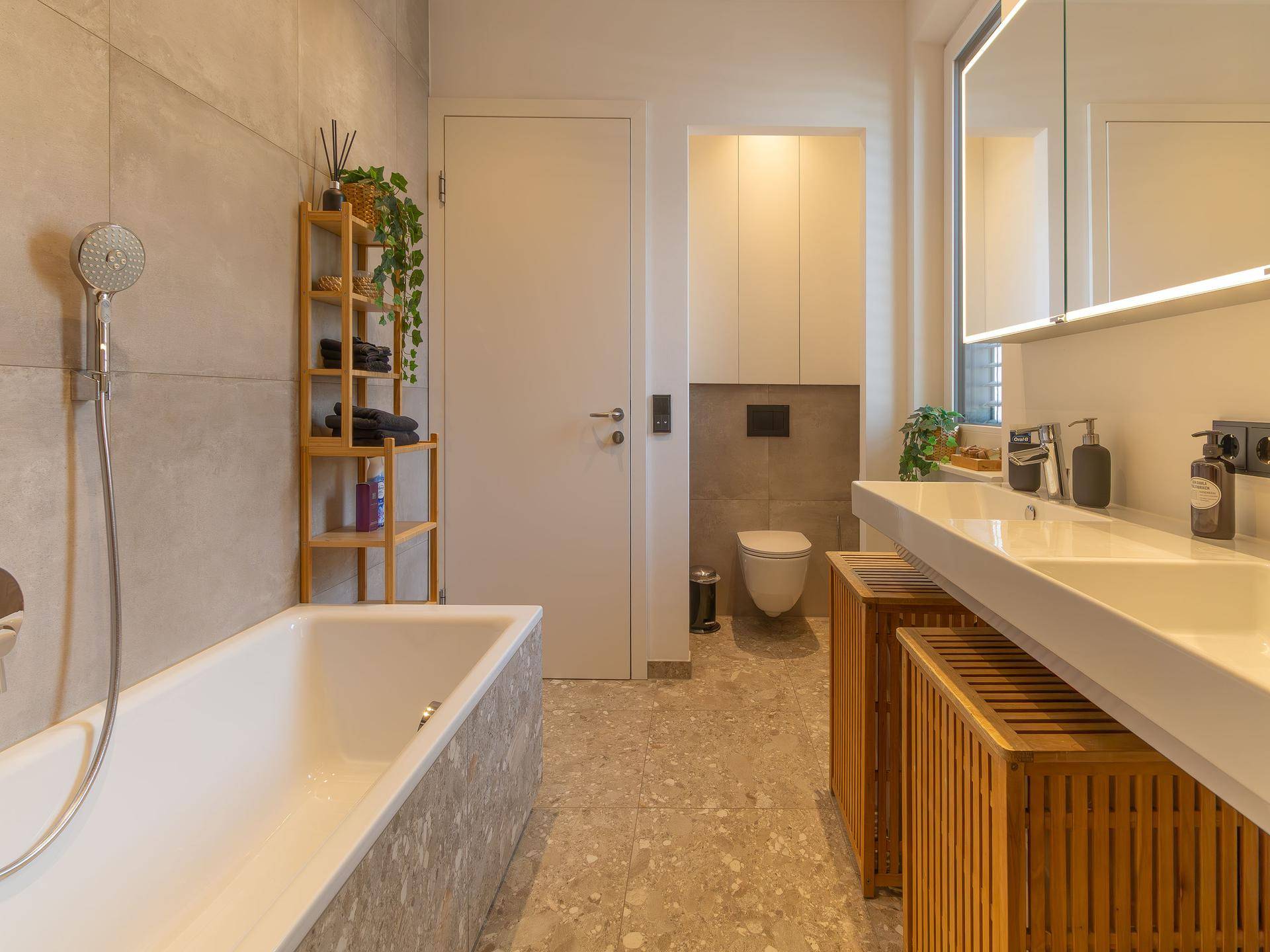 Modernes Badezimmer mit Badewanne, Doppelwaschbecken und eleganten grauen Fliesen.