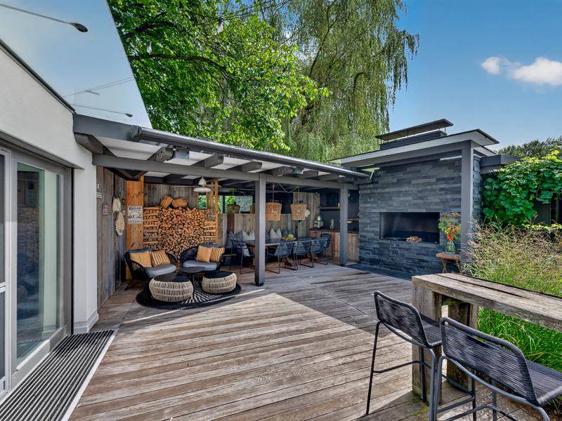 Überdachte Terrasse mit Essbereich, Lounge-Möbeln und Außenkamin für gesellige Stunden.