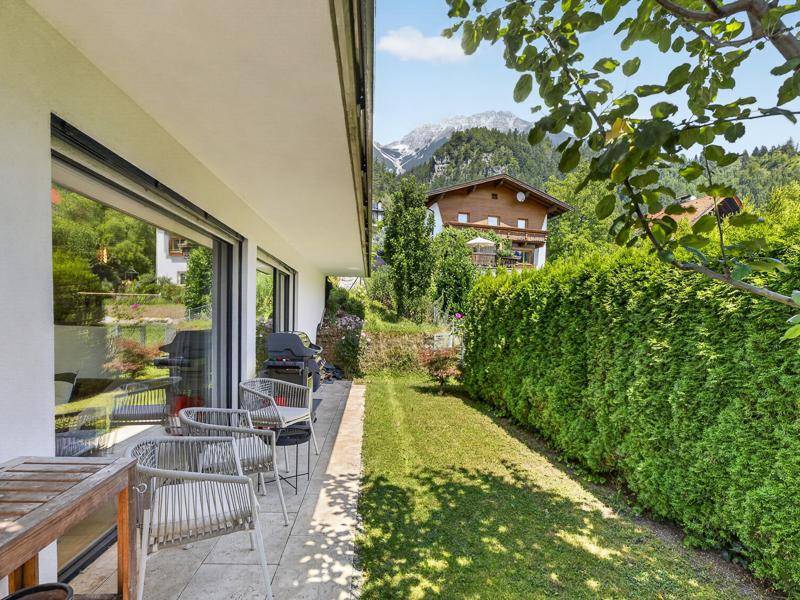 Gemütliche Terrasse mit Gartenmöbeln, Grillplatz und Blick auf die grüne Berglandschaft.