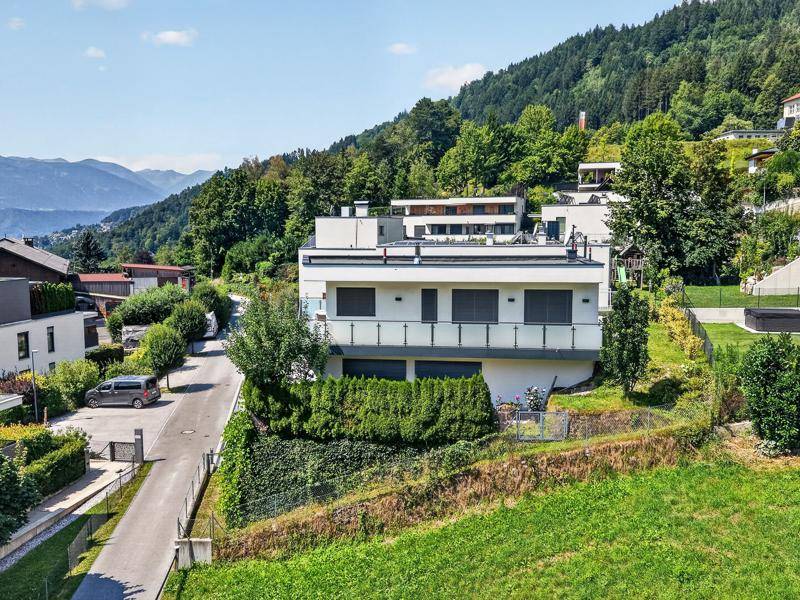 Moderne Wohnanlage in Hanglage mit weißer Fassade und Blick auf die umliegende Berglandschaft.